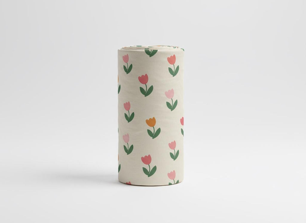 Upright roll of fabric printed with the Spring Tulip pattern of small pink and orange tulips on cream.