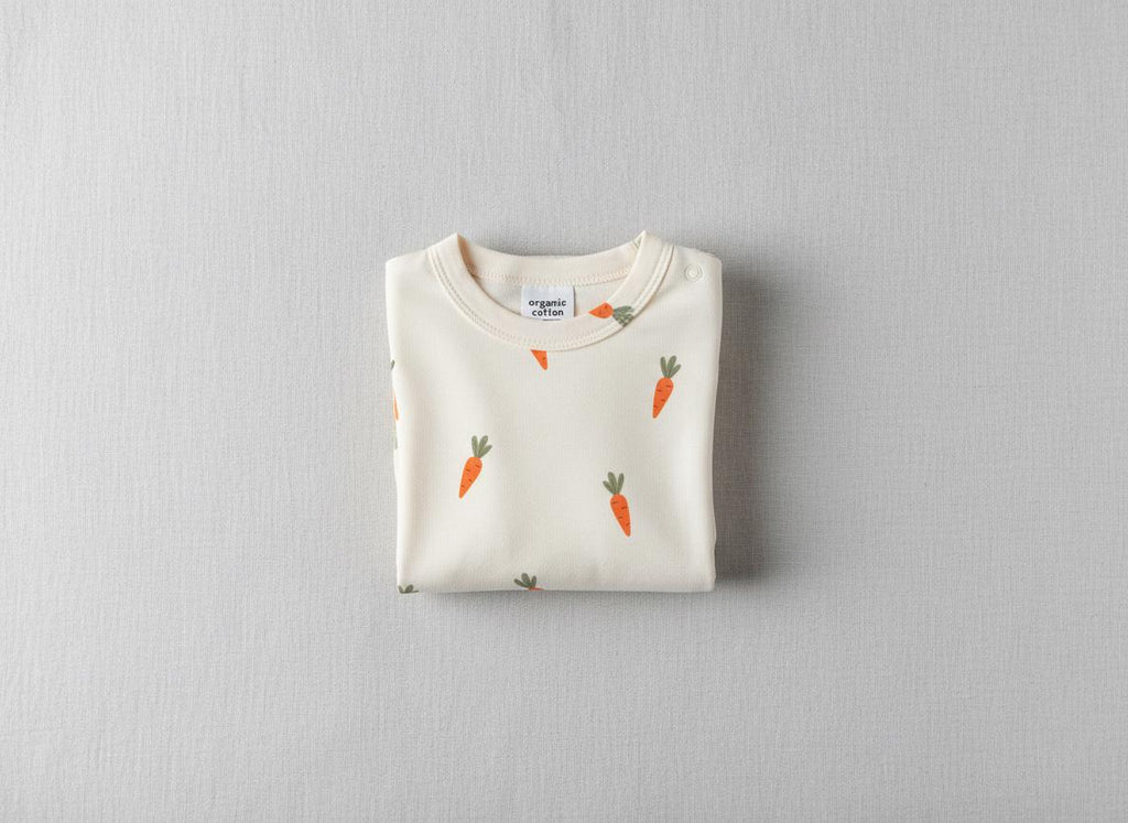 Folded cream children's top printed with the Carrot pattern of small orange carrots with green tops.
