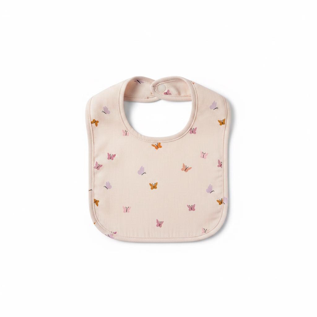 A light beige baby bib featuring a repeating pattern of small butterflies in shades of pink, lavender, and mustard yellow. The bib has a rounded shape with a single snap closure at the top neck strap and finished edges throughout.