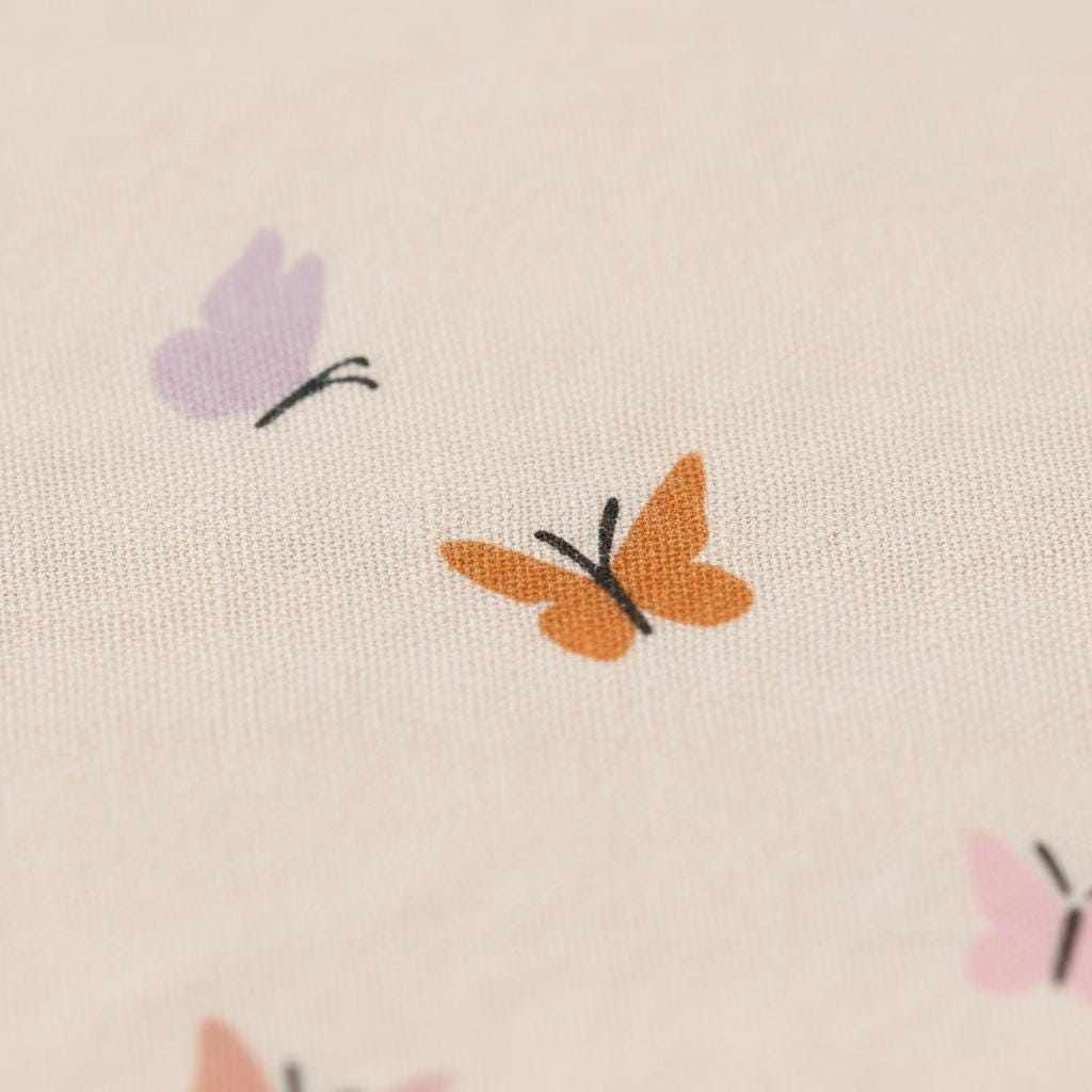 Close-up of cream fabric printed with the Butterfly pattern of small lilac, orange and pink butterflies.