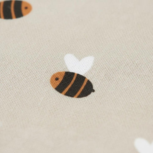 Close-up of beige linen fabric printed with the Bee pattern of little black and orange honey bees with white wings.