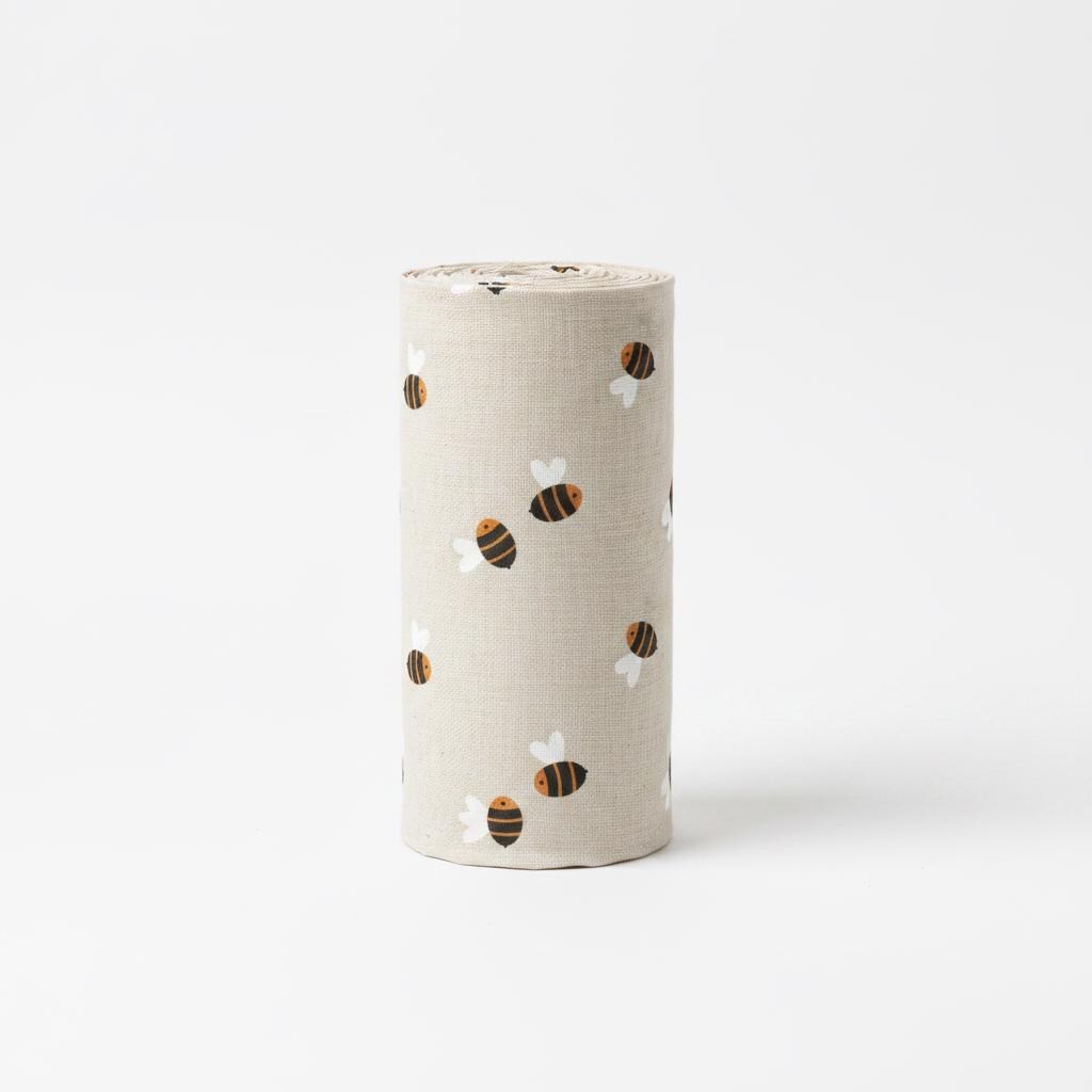 Upright roll of beige fabric printed with the Bee pattern of small honey bees.