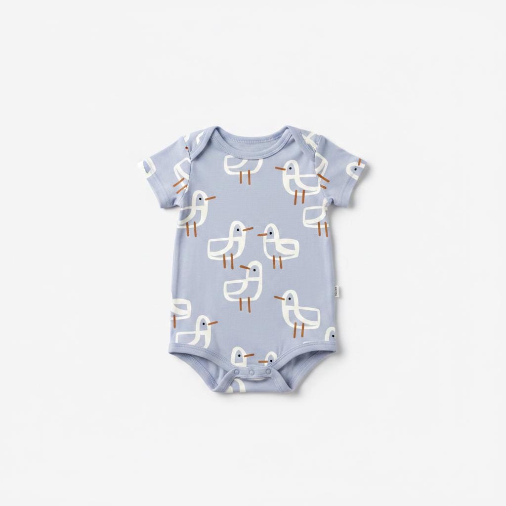 A light blue short-sleeved baby bodysuit featuring an all-over pattern of white stylised birds with brown beaks and legs. The garment has a round neckline and three snap closures at the bottom for easy access and secure fastening.