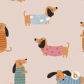 A repeating pattern on a light pink background featuring cartoon dachshunds wearing various sweaters. The dogs are tan with black ears and are dressed in blue cloud-print, pink polka-dot, orange striped, and blue striped sweaters.