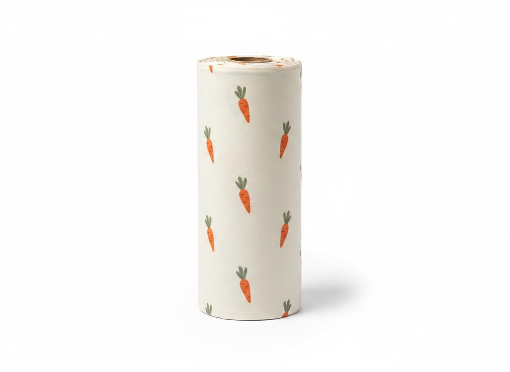 A cylindrical roll of off-white paper featuring a repeating pattern of small orange carrots with green leafy tops. The carrots are oriented in various directions across the surface of the paper roll, which has a visible cardboard core.