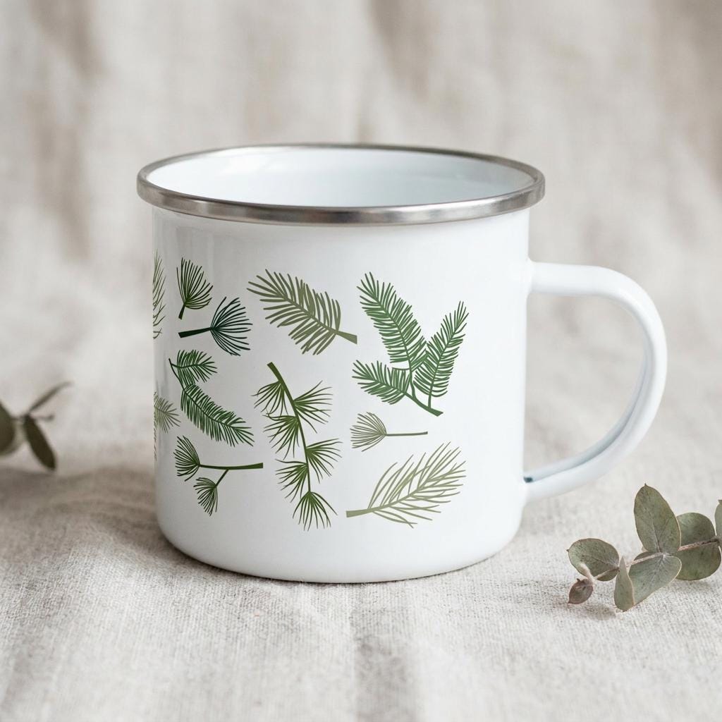 A white enamel mug featuring a pattern of various green pine needles and evergreen branch illustrations. The mug has a smooth white finish, a silver-toned metal rim around the top edge, and a matching white handle on the right side.