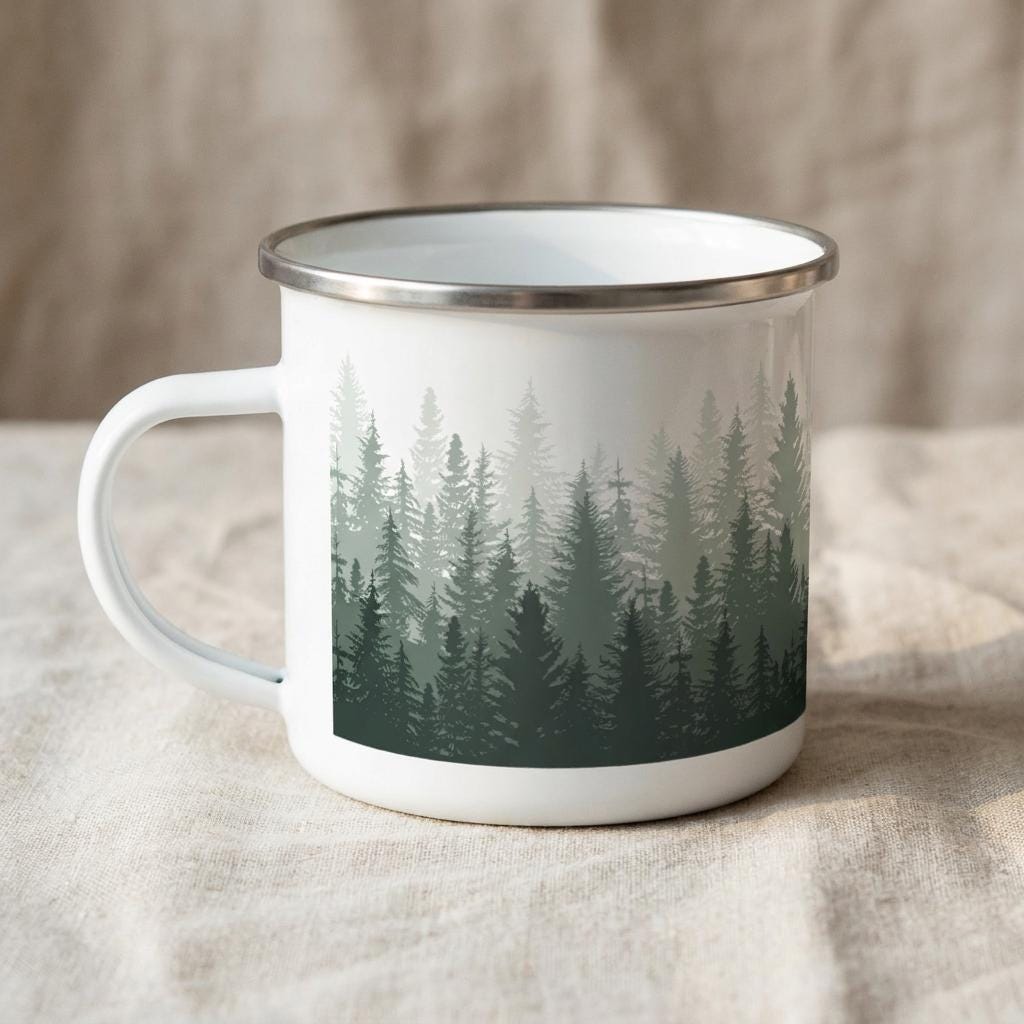 A white enamel mug featuring a wrap-around graphic print of a dense forest with pine trees in varying shades of dark green and sage. The mug has a smooth, glossy finish and a silver-toned metal rim around the top edge and handle.