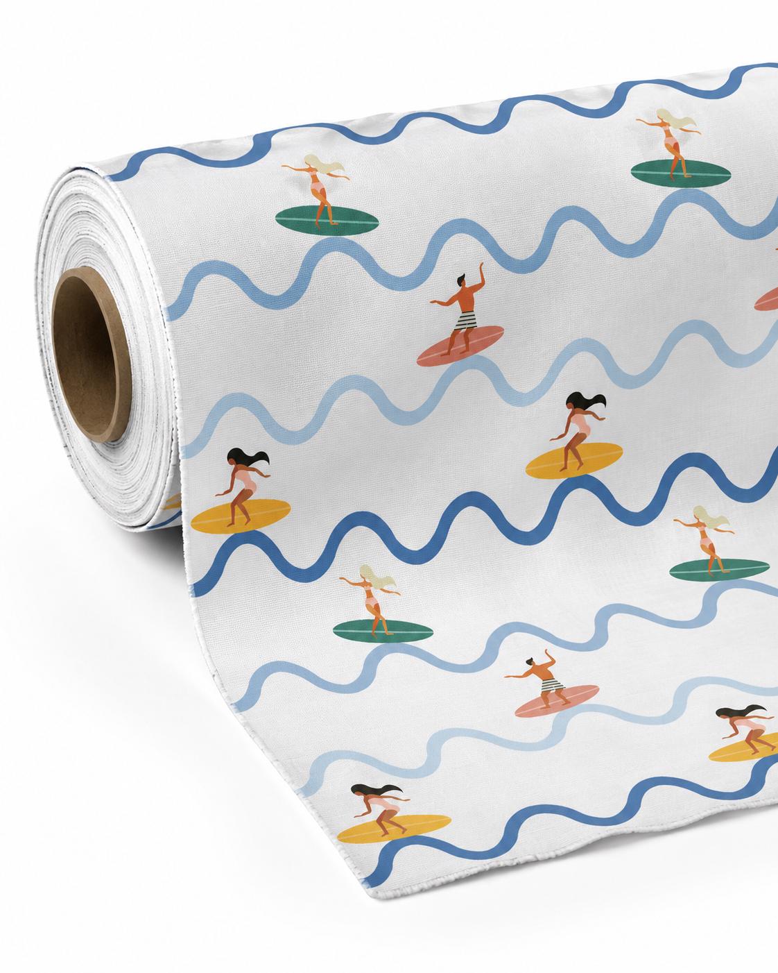 A roll of white fabric featuring a repeating pattern of surfers on colourful surfboards. The design includes wavy horizontal lines in light and dark blue, interspersed with illustrations of people surfing on yellow, green, and coral boards.
