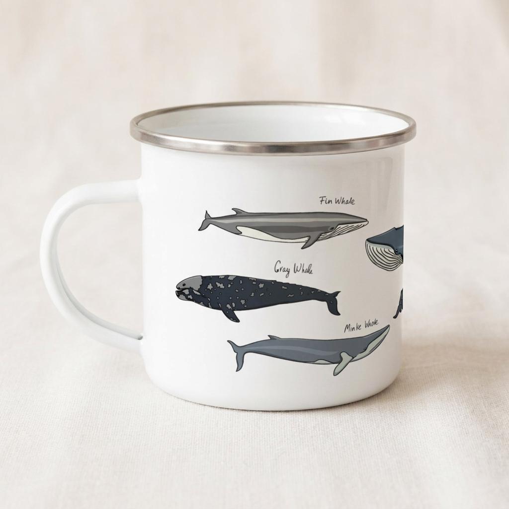 A white enamel mug with a silver rim and handle, featuring illustrations of various whale species including a Fin Whale, Gray Whale, and Minke Whale, each labelled with its respective name in black text printed on the side of the mug.