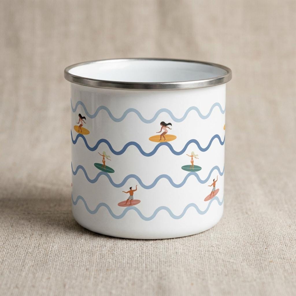 A white enamel mug with a silver-toned rim featuring a repeating pattern of light and dark blue wavy lines. The design includes small illustrations of people surfing on colourful surfboards scattered across the mug's exterior surface.