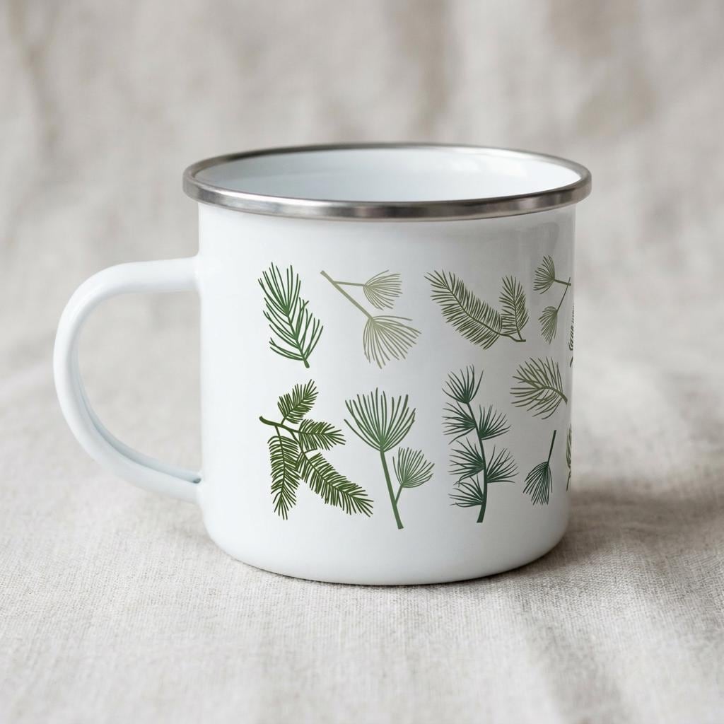 A white enamel mug with a silver-toned rim and a handle on the left side. The exterior features a repeating pattern of various green pine needles and evergreen branch illustrations arranged across the surface of the white metal cup.