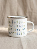 Botanical Leaf enamel mug: white camping mug with a silver rim, covered in rows of small leaf and fern illustrations in green, navy and blue.
