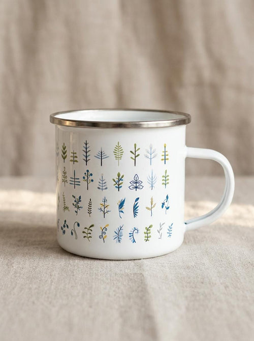 Botanical Leaf enamel mug: white camping mug with a silver rim, covered in rows of small leaf and fern illustrations in green, navy and blue.