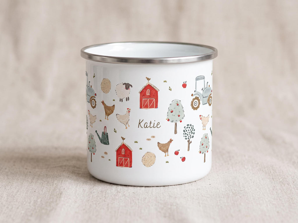 A white enamel mug with a silver rim featuring a colourful farm-themed pattern of red barns, tractors, chickens, sheep, trees, and apples. The name Katie is printed in the centre in a dark grey script font on the front of the mug.