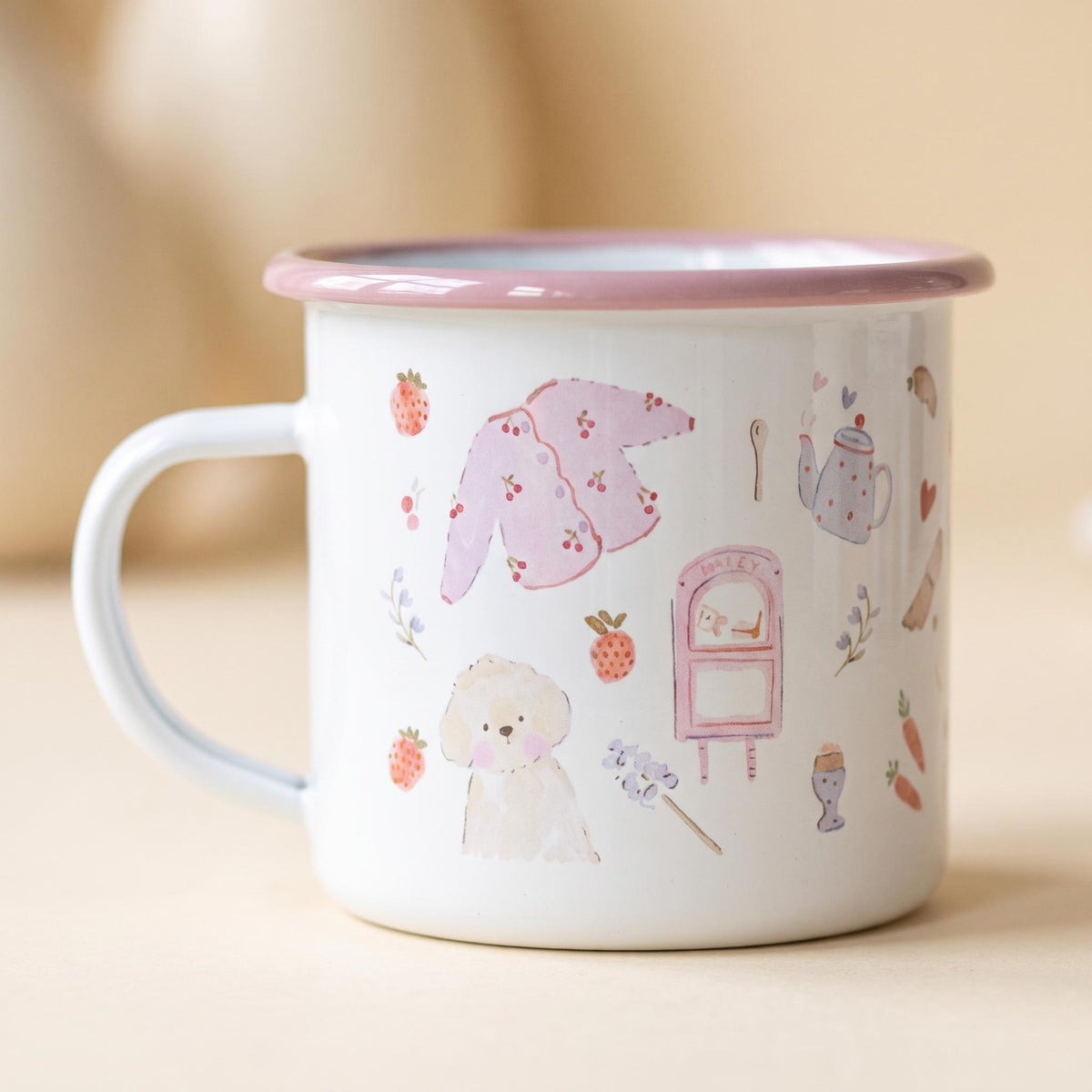 A white enamel mug with a pink rim and handle, featuring a repeating pattern of watercolour illustrations including a pink cardigan, a small dog, a mailbox, strawberries, carrots, a teapot, and small floral sprigs on the exterior.