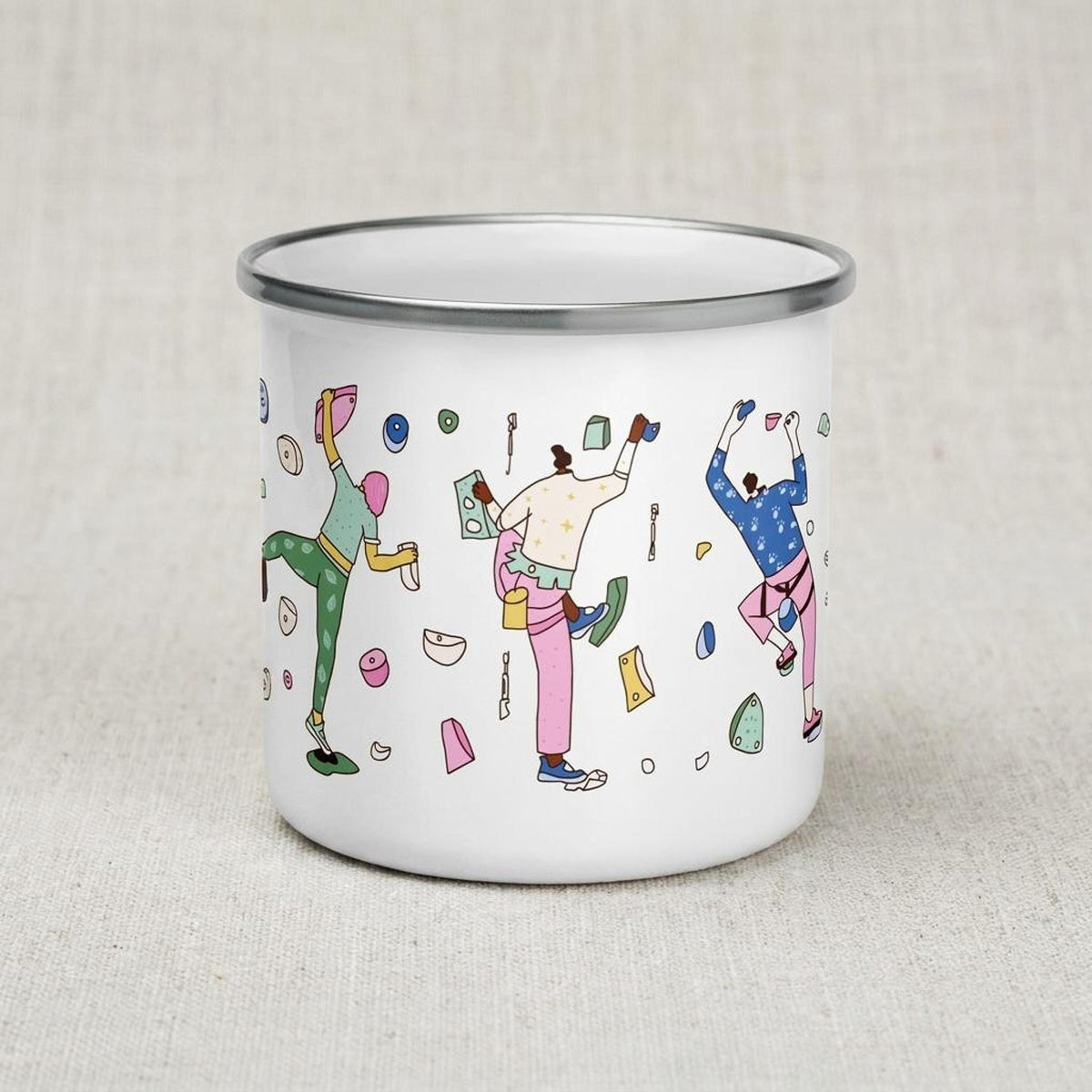 A white enamel camping mug displays multiple illustrated rock climbers.