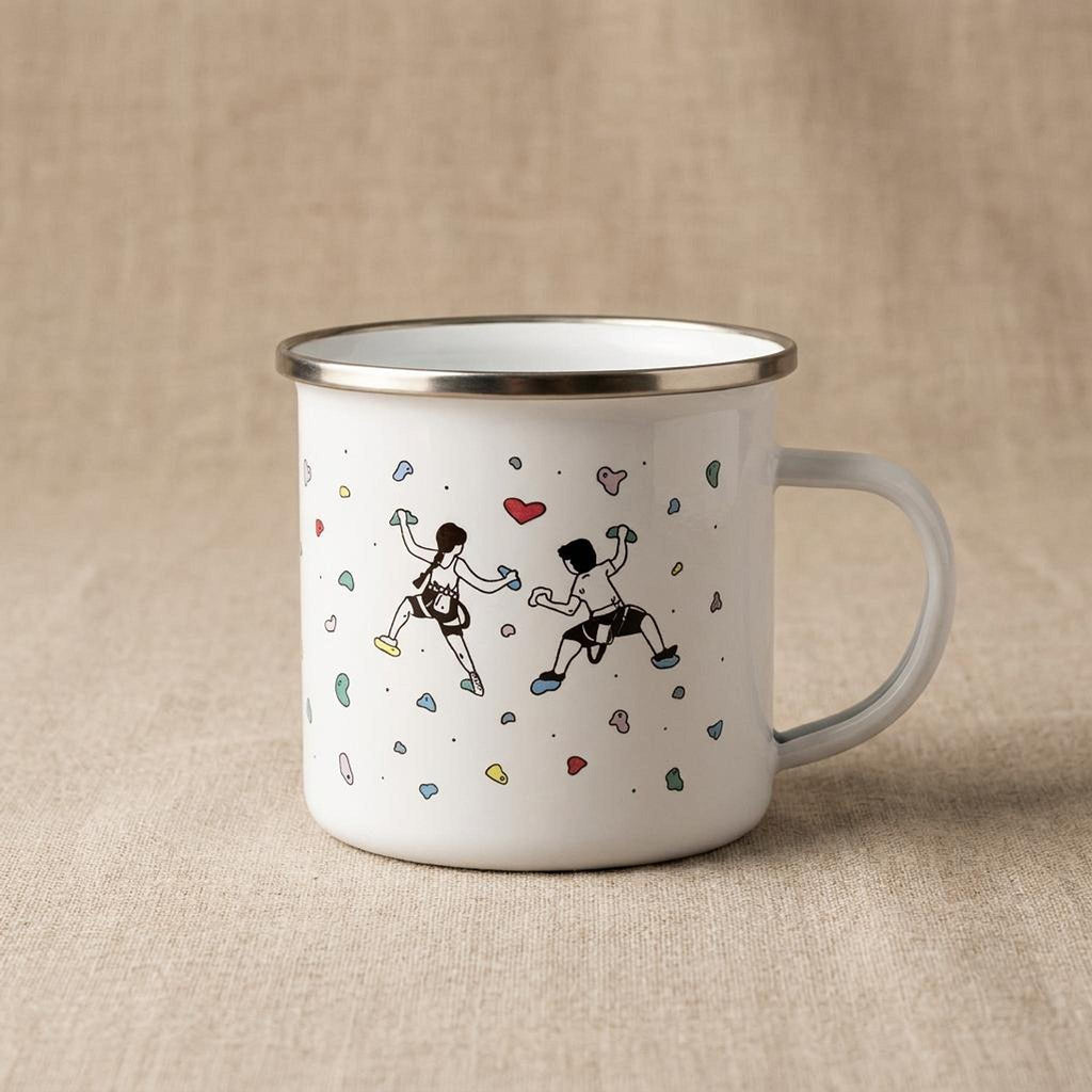 A single white enamel mug showing an illustration of two rock climbers and colorful holds against a neutral fabric background.