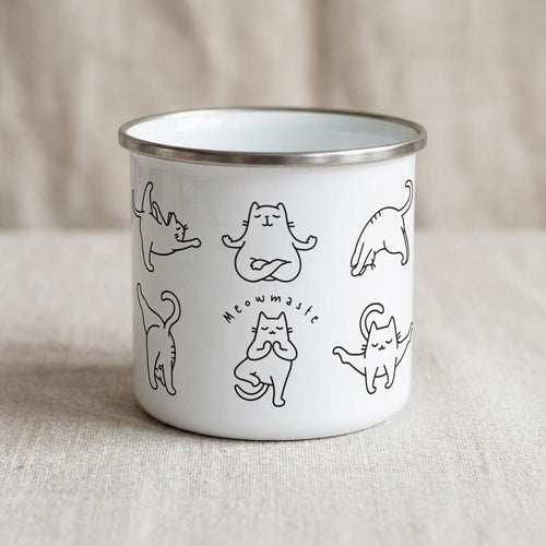A white enamel camping mug featuring black line drawings of cats in various yoga poses and the text Meowmaste.