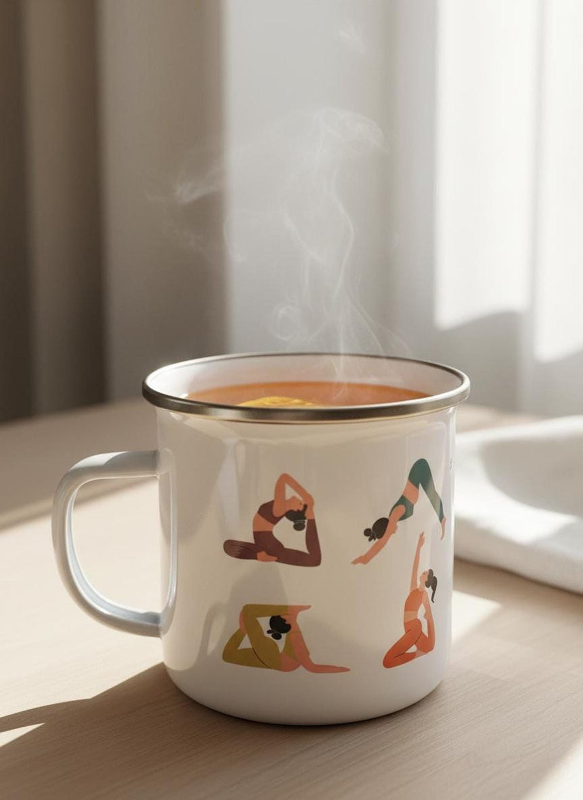 Steaming hot beverage in a white enamel mug with yoga pose graphics, sitting on a wooden surface.