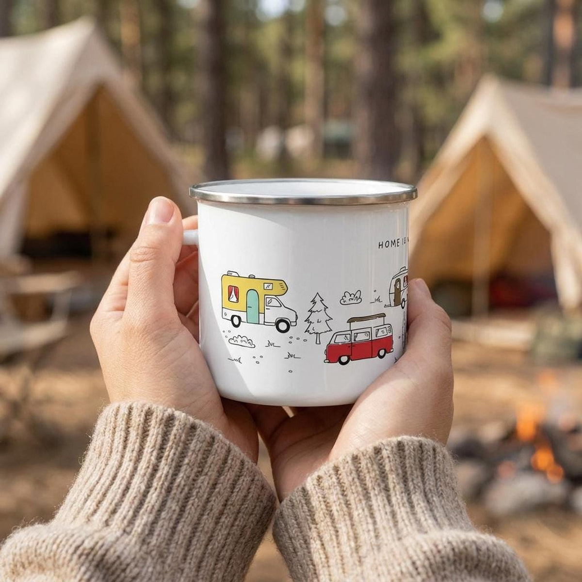 Person wearing a beige knit sweater holding the campervan enamel mug in front of a campsite with two tents.