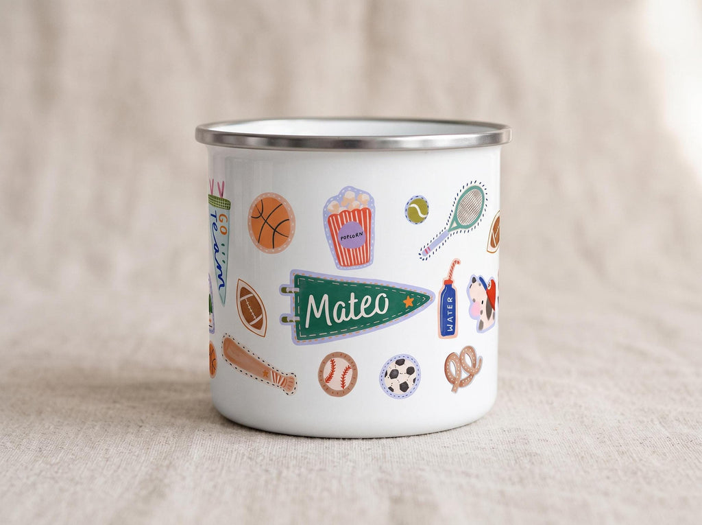 A close-up of a white enamel mug featuring a green pennant sticker with the custom name Mateo, along with other sports stickers.