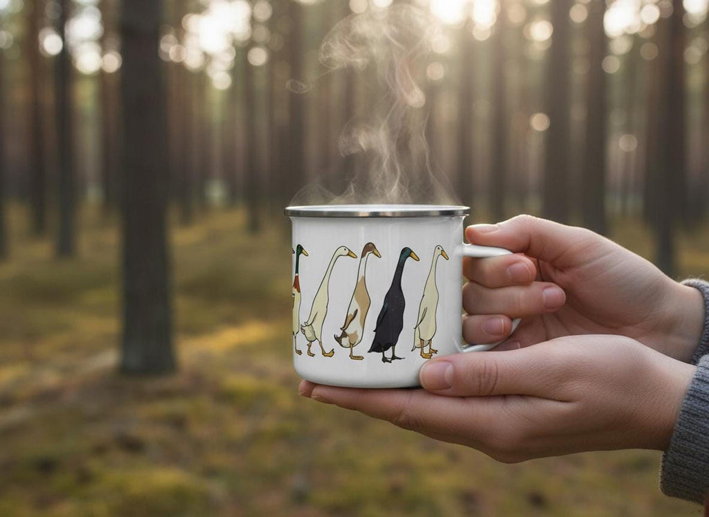 Hands holding a steaming enamel mug with a runner duck graphic against a softly lit pine forest background.