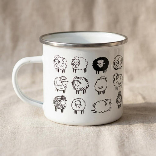 A white metal enamel mug with a silver rim displays a grid pattern of cute black cartoon sheep illustrations against a neutral textured fabric background.