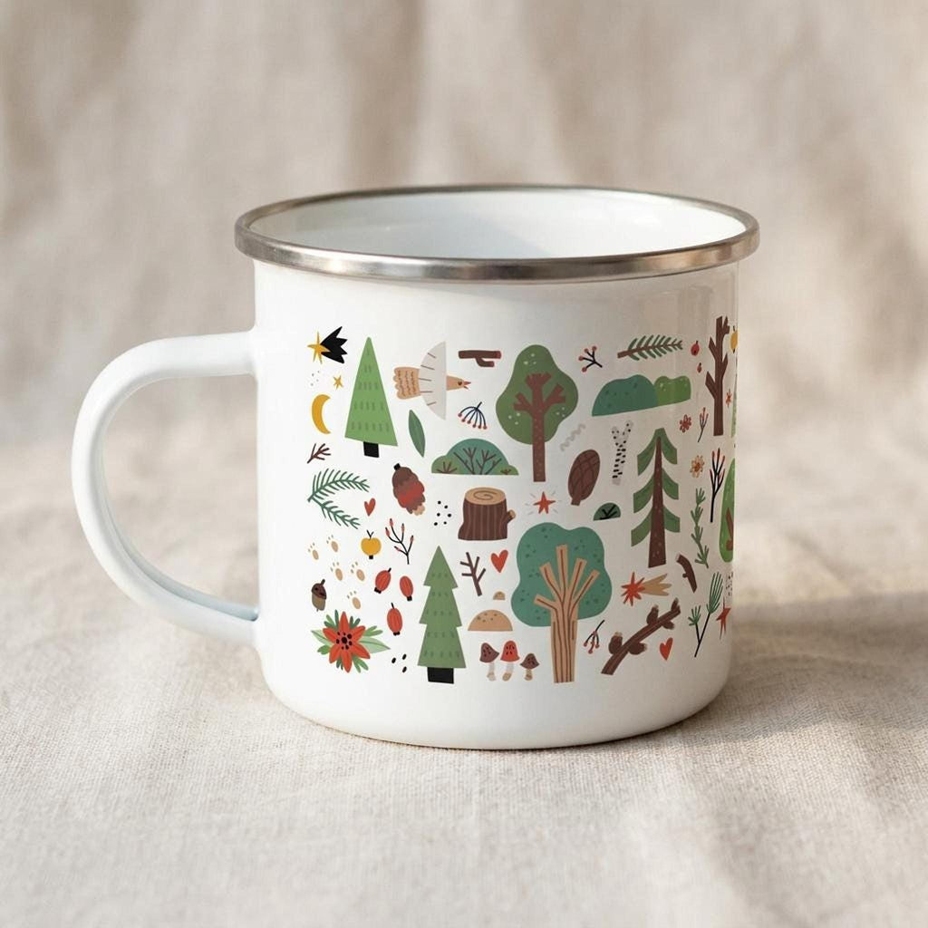 A white enamel mug with a silver rim sits on a beige fabric surface, displaying an illustrated forest pattern including trees, birds, and pinecones.