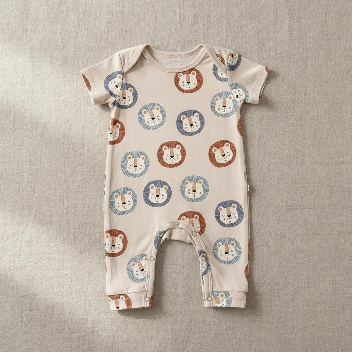 Short-sleeve baby onesie laid flat, showcasing an all-over seamless pattern of blue and brown cartoon lions.