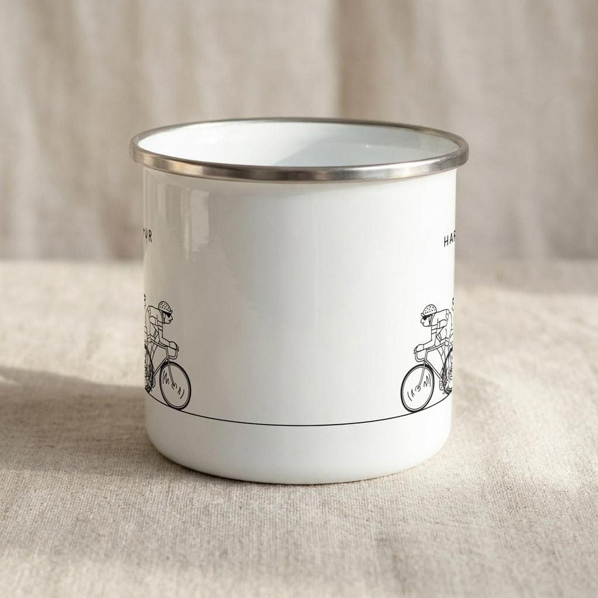 A close-up view of the back side of the white enamel mug resting on a fabric backdrop.