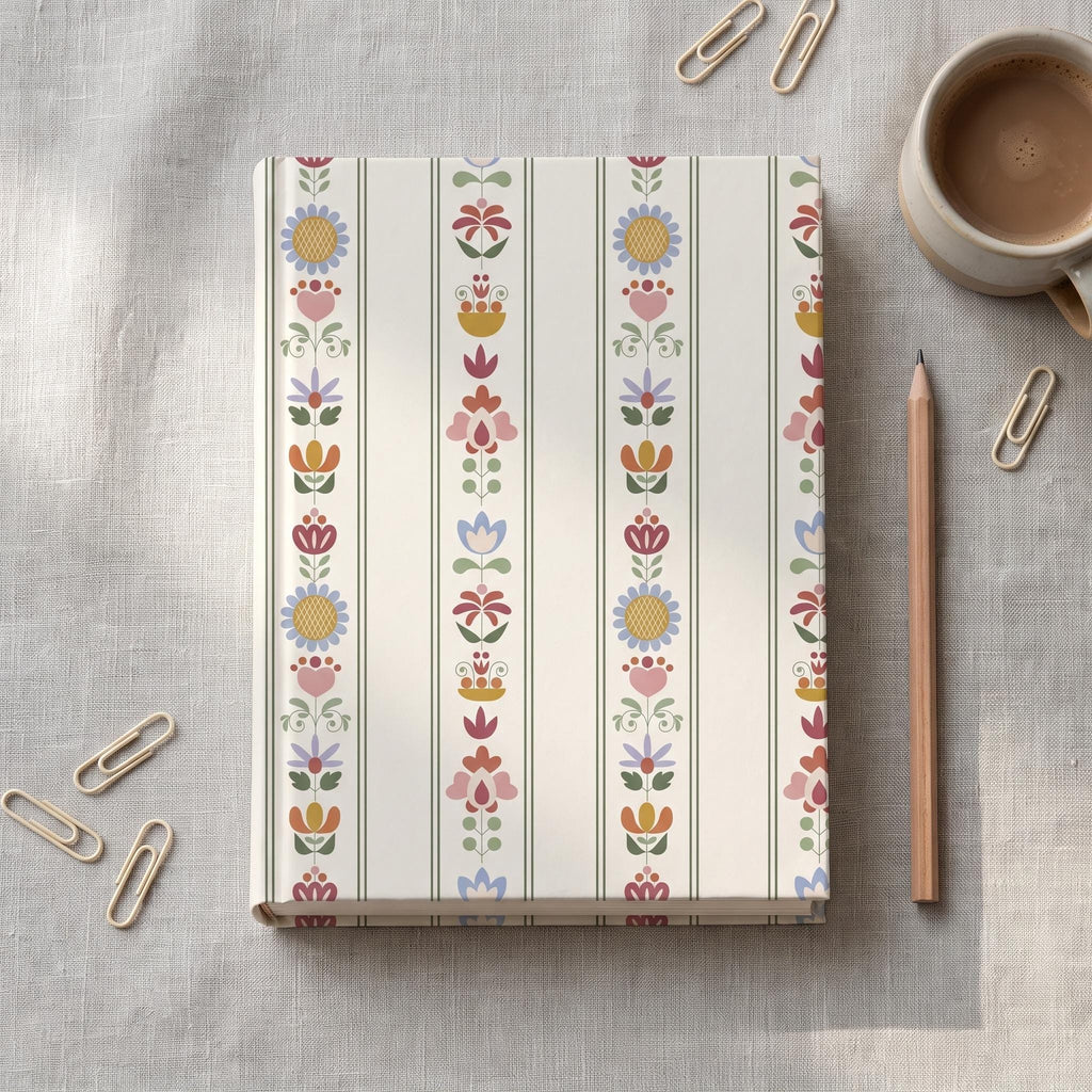 A hardback notebook featuring a cream-coloured cover with vertical stripes and a repeating folk-art floral pattern in shades of blue, pink, yellow, and green. The design consists of stylised flowers and leaves arranged in columns.