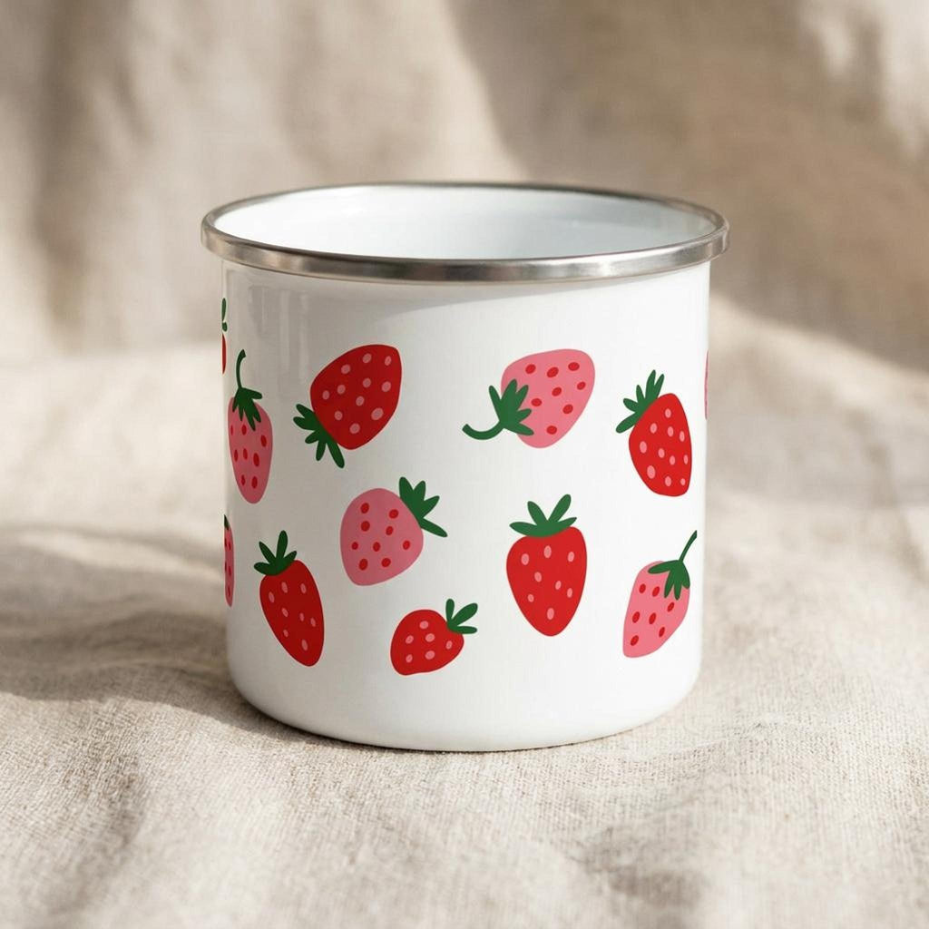 A white enamel mug with a silver rim displays a scattered strawberry pattern against a neutral textured background.