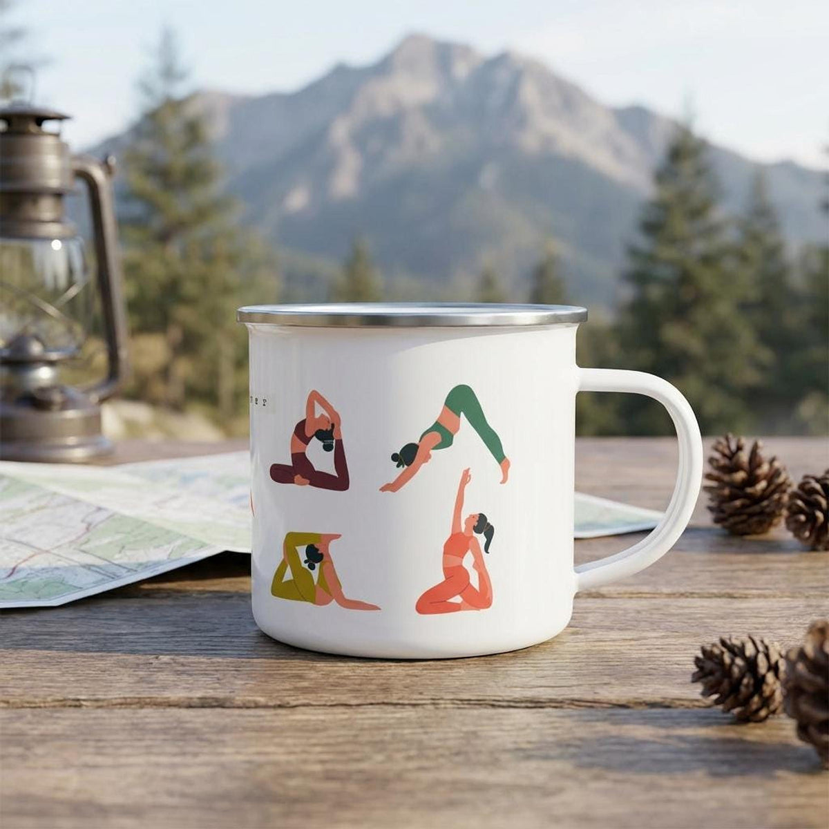 White enamel yoga mug on a rustic outdoor table with pinecones, a map, a lantern, and mountains in the distance.