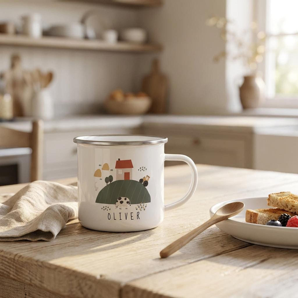 A personalized white enamel mug with a cartoon farm graphic sits on a wooden table next to a plate of toast and a napkin in a kitchen.