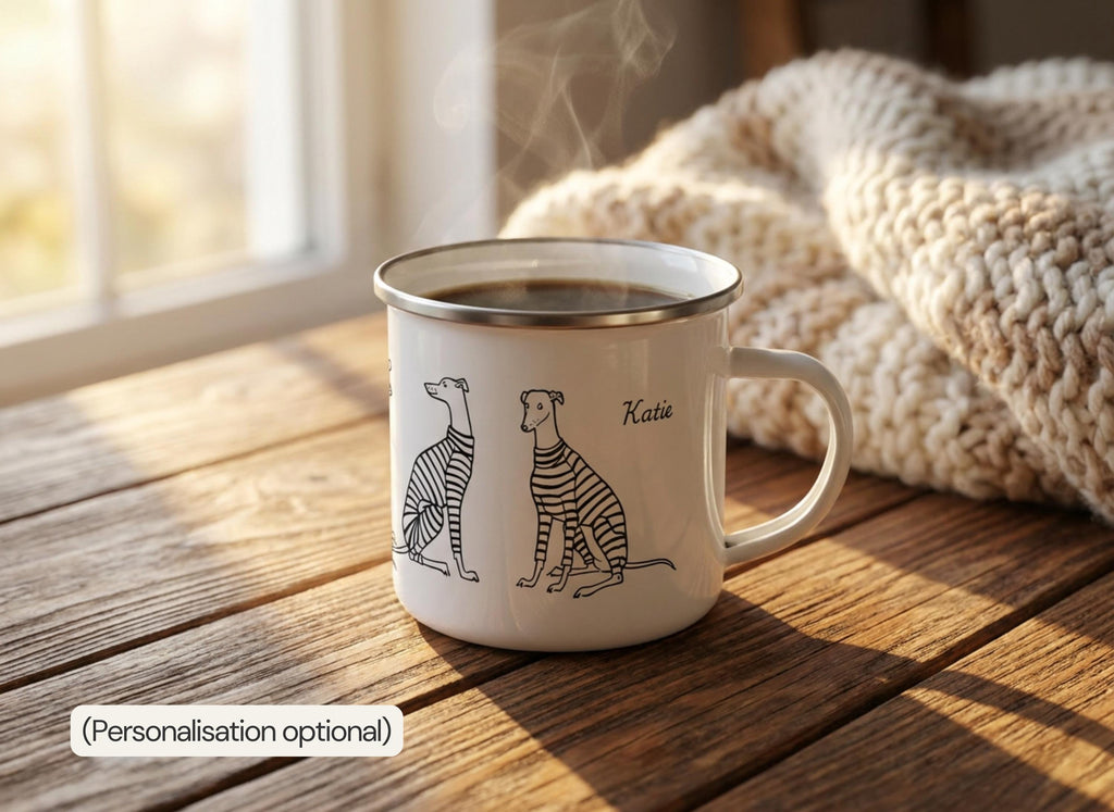 A steaming white enamel mug with a whippet illustration and the personalized name Katie printed on it rests on a wooden table near a window and a knitted blanket.