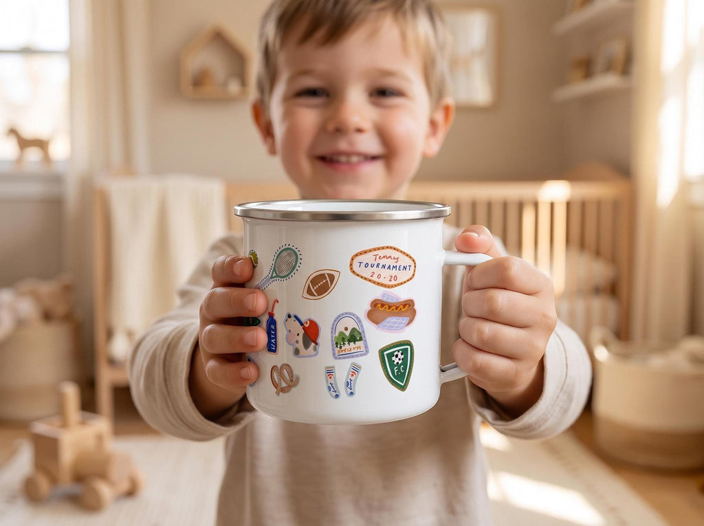 A young smiling child holds up a white sports enamel mug with both hands in a brightly lit room.