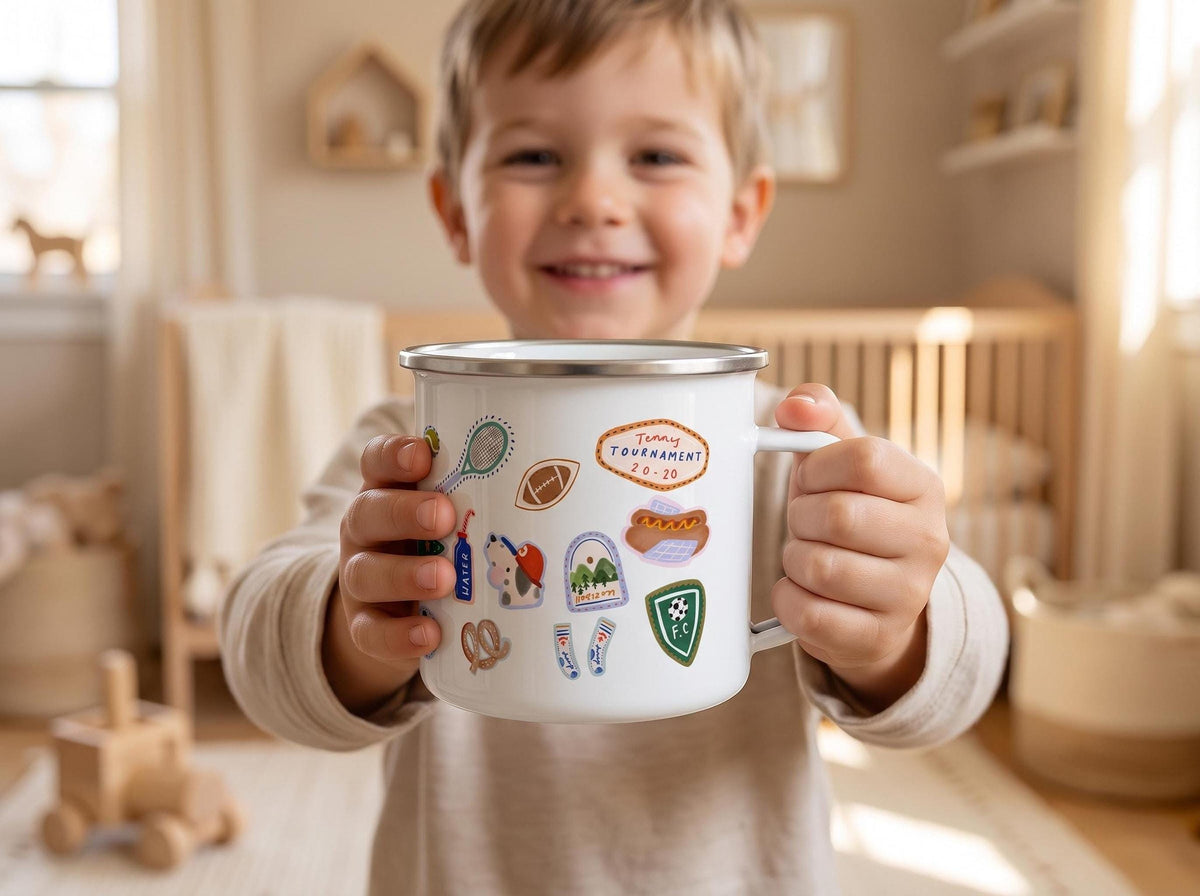 A young smiling child holds up a white sports enamel mug with both hands in a brightly lit room.