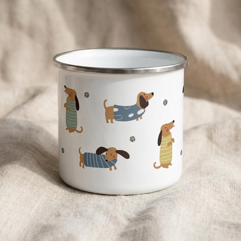 The same white enamel mug rotated to show a different arrangement of cartoon dachshunds wearing patterned jumpers.