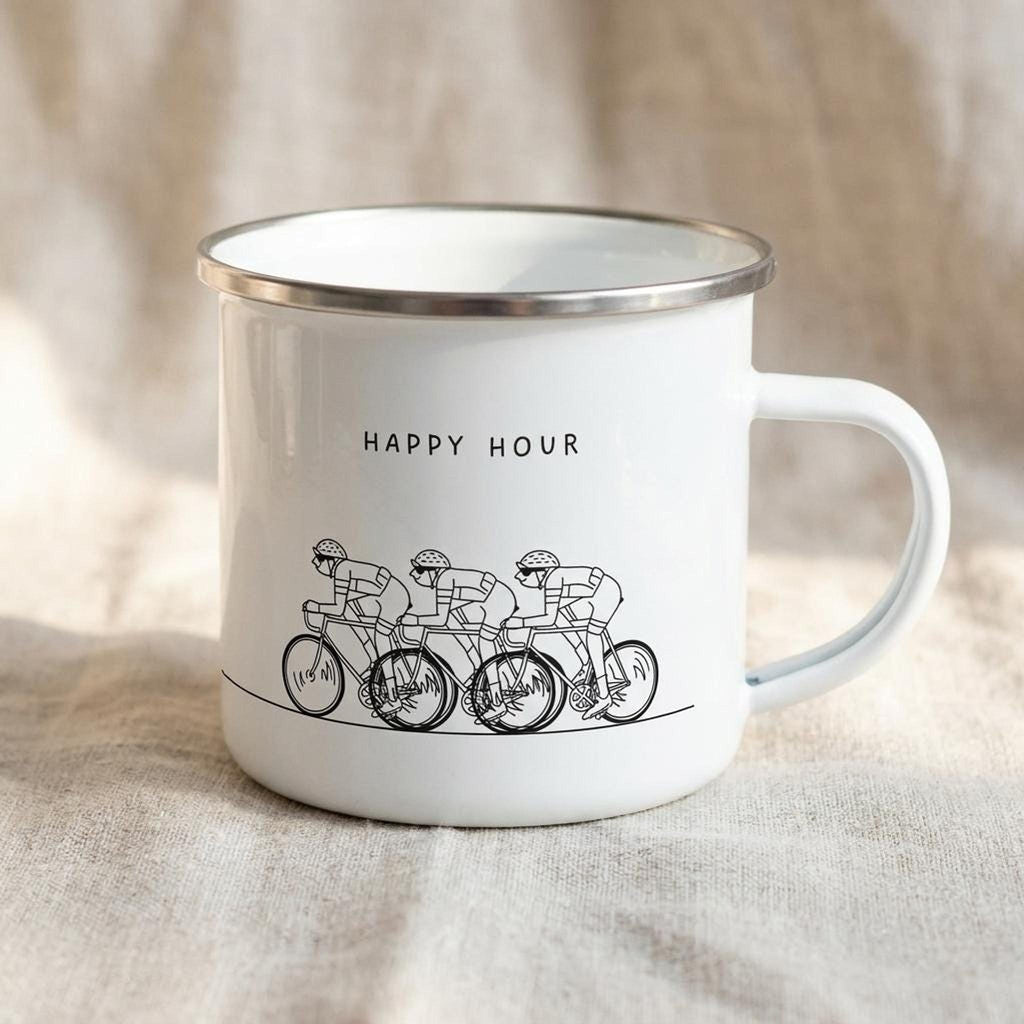 A white enamel mug with a silver rim sits on a neutral fabric surface, featuring a black-ink illustration of three cyclists and the text HAPPY HOUR.