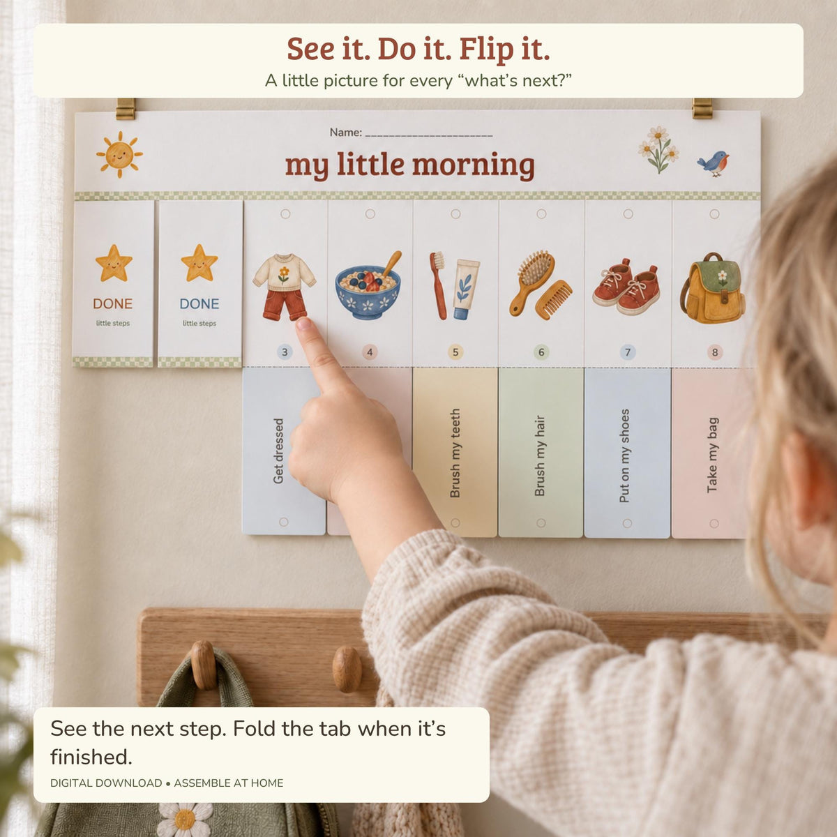 A child's hand points to the get dressed icon on a hanging daily morning routine chart.