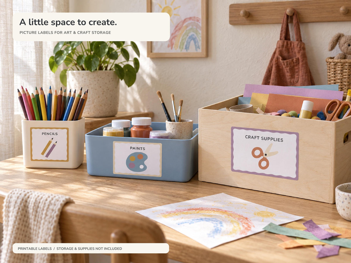 A sunlit Scandinavian art corner with labelled storage for PENCILS, PAINTS and CRAFT SUPPLIES on an oak table. Colourful paper, pencils and a child drawing show a practical home setup.