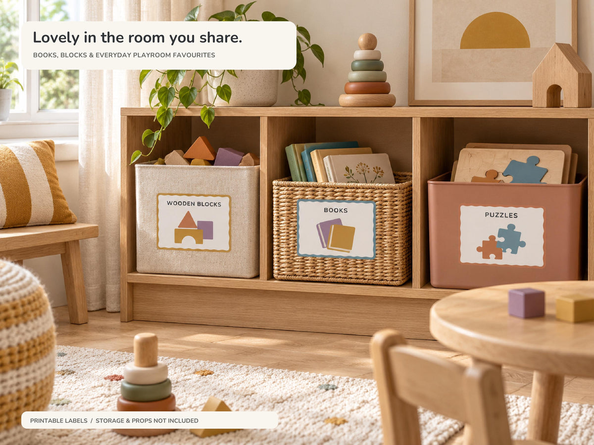 A shared family playroom with oak shelving and labelled storage for WOODEN BLOCKS, BOOKS and PUZZLES. Earthy colours, a child table and an ochre striped cushion complete the scene.