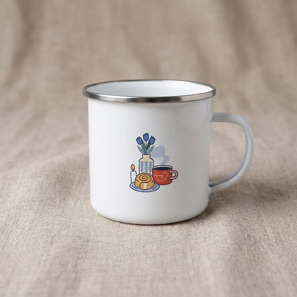 A white enamel mug with a silver rim displays a graphic of blue tulips in a vase beside a pastry, a lit candle, and a red mug.