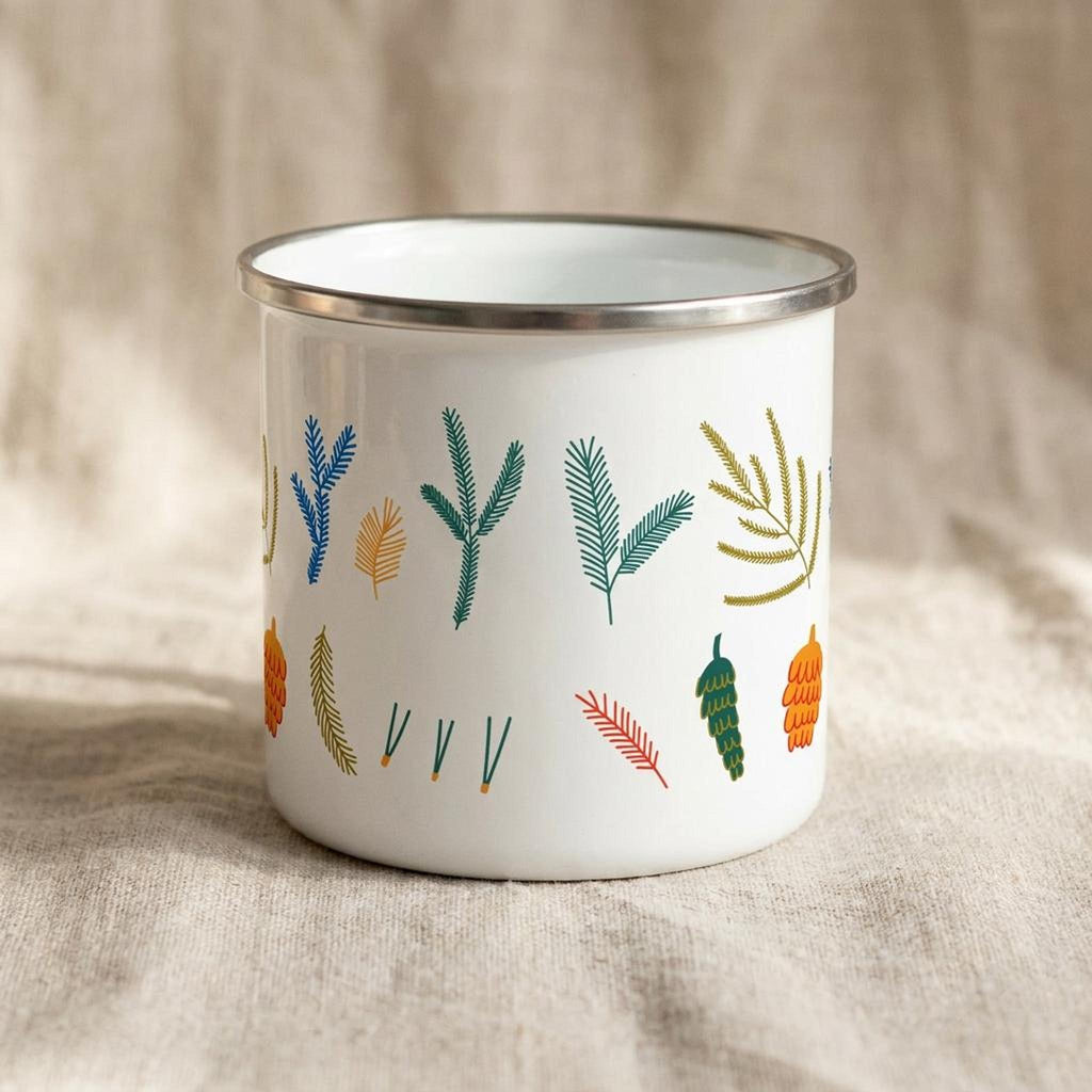 Front view of the white enamel mug showing a different assortment of colorful pine and cone motifs.