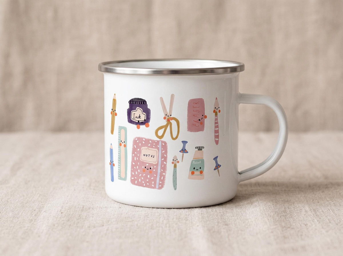 A white enamel mug with a silver rim and handle shows a pattern of cute cartoon stationery items such as a notebook, ink bottle, and scissors.