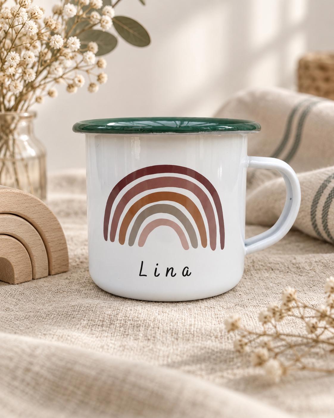 A white enamel mug with a dark green rim and a handle. The front features a graphic of a multi-coloured rainbow in shades of brown, rust, and beige. Below the rainbow, the name Lina is printed in a simple, black, sans-serif font.