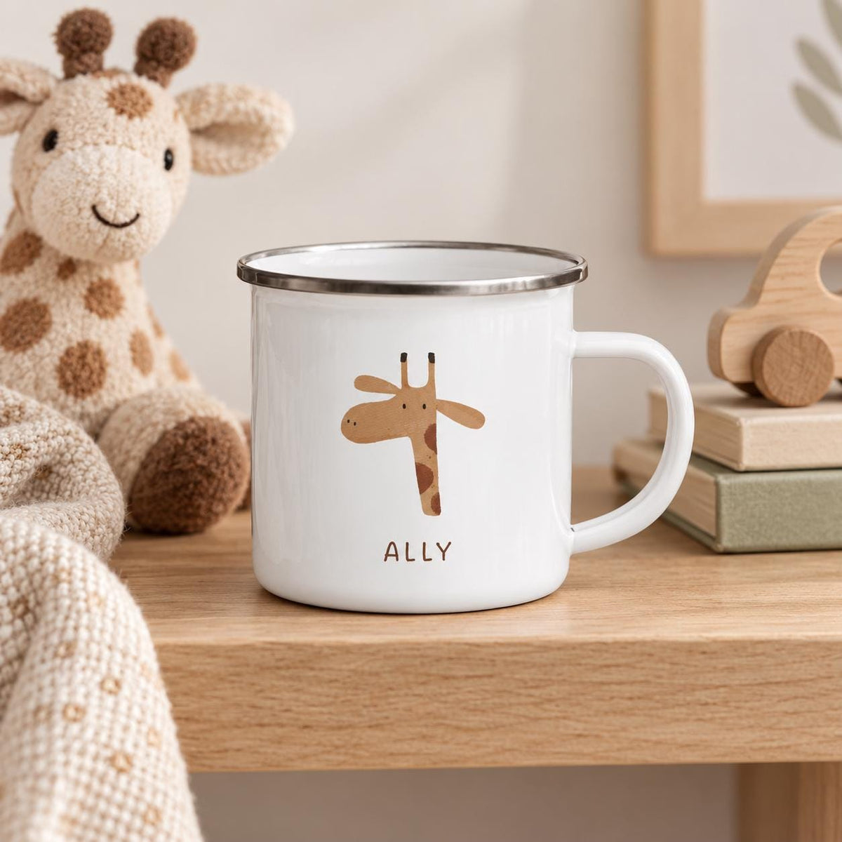 A white enamel mug with a silver rim, featuring a brown giraffe illustration and the name ALLY printed in brown text on the front. The mug has a single handle and a smooth, cylindrical body, presented as a functional drinkware item.