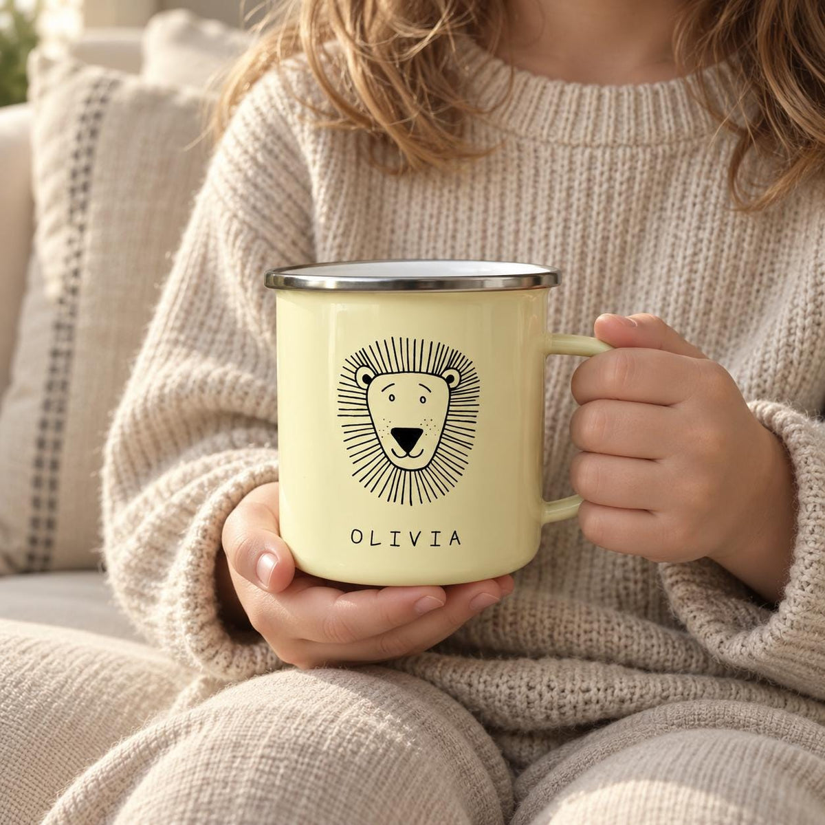 A pale yellow enamel mug featuring a black line drawing of a lion's face and the name OLIVIA printed in black capital letters below the illustration. The mug has a silver-coloured metal rim and a matching pale yellow handle.