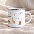 A white enamel mug with a silver rim and handle, featuring a colourful pattern of various safari animals including a giraffe, elephant, lion, flamingo, crocodile, meerkats, and snakes, with the name ALFIE printed in black text.