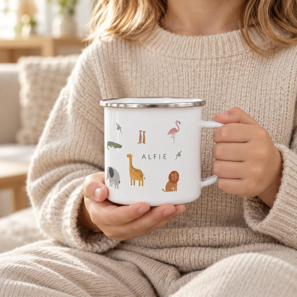A white enamel mug with a silver rim and handle, featuring colourful illustrations of a giraffe, lion, elephant, flamingo, crocodile, and snakes, with the name ALFIE printed in black capital letters in the centre of the design.